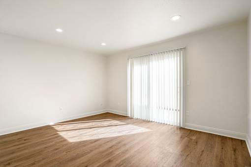 A room with wooden floors and a window with white curtains.