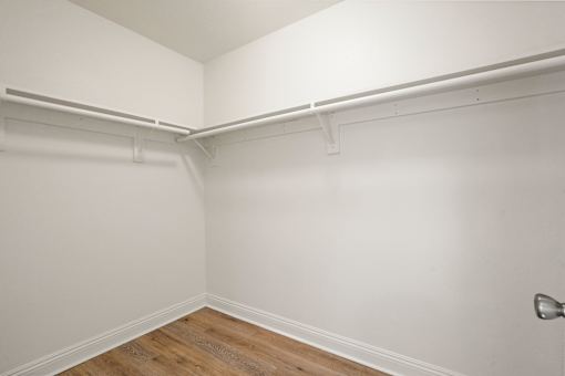 A white wall with a wooden floor and a door handle.