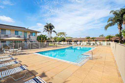 A pool surrounded by chairs and a fence.
