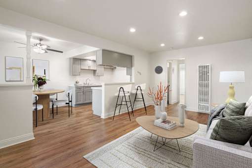 A modern living room with a kitchen in the background.