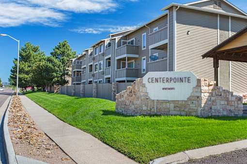 A stone sign that says Centerpointe Apartments sits in front of a building.