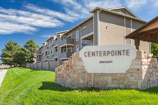 A stone sign that says Centerpointe Apartment in front of a building.