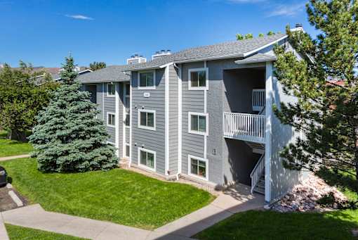 A grey apartment building with a green lawn in front.