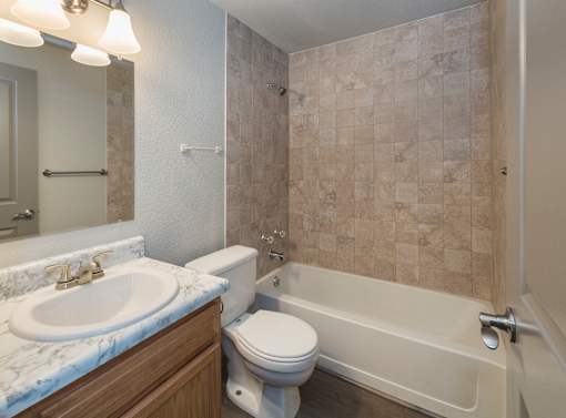 A bathroom with a marble countertop and a tiled shower.