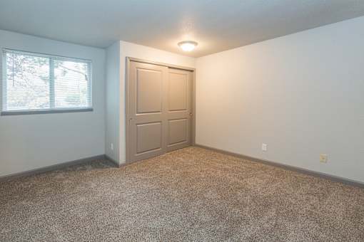 A room with a carpeted floor, a door, and a window.