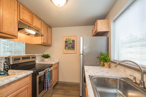 A kitchen with a refrigerator, sink, and stove.