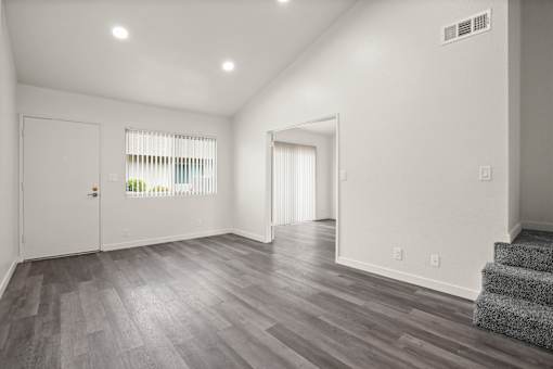 A room with a staircase and a window with blinds.