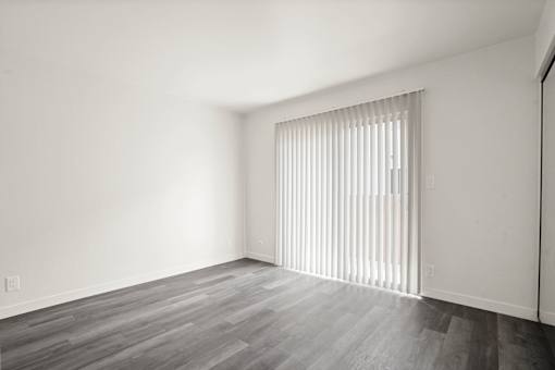 A room with a window covered by vertical blinds.
