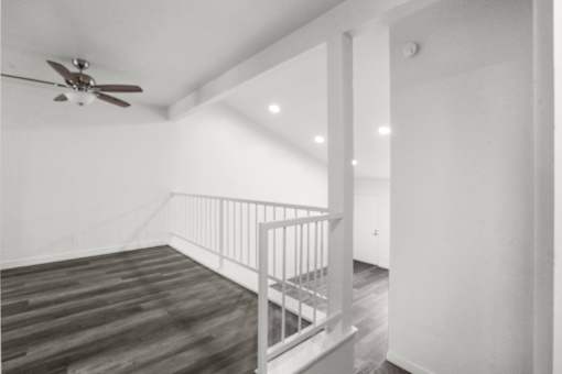 A room with a ceiling fan and a staircase.