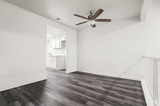 A room with a ceiling fan and wooden flooring.