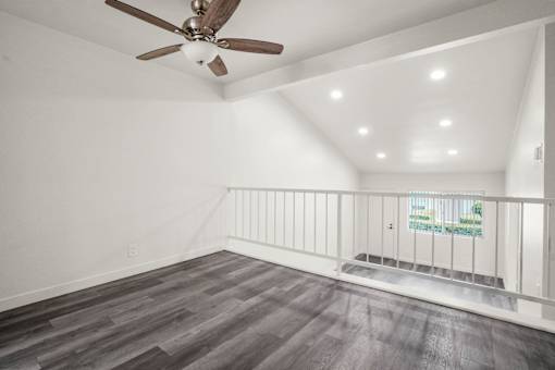 A room with a ceiling fan and wooden flooring.