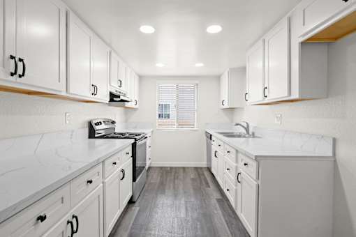 A kitchen with white cabinets and a marble countertop.