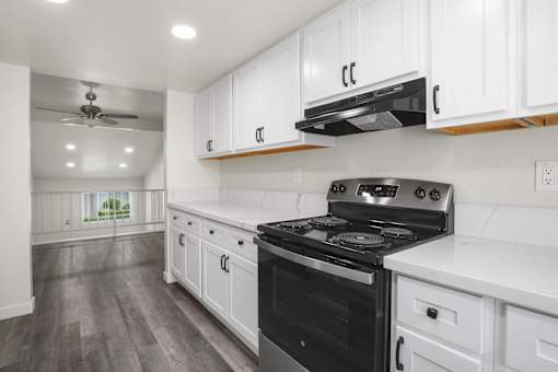 A modern kitchen with a black stove top oven and white cabinets.