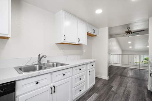 A kitchen with white cabinets and a stainless steel sink.