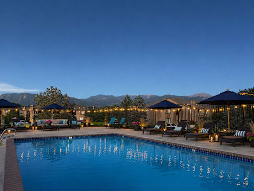 A large swimming pool surrounded by lounge chairs and umbrellas.