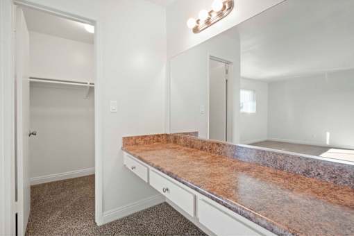 A bathroom with a marble countertop and a large mirror above it.