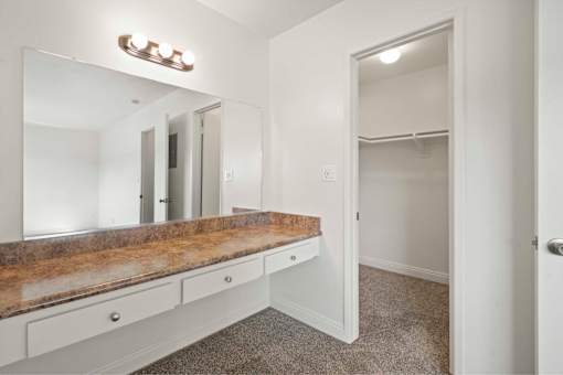 A white bathroom with a vanity and a mirror.