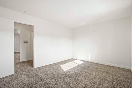 A room with a carpeted floor and a doorway leading to another room.