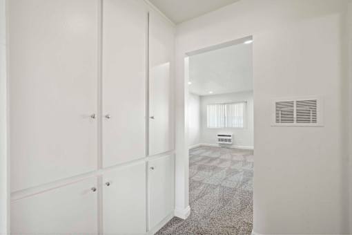 A white hallway with a carpeted floor and a white door on the right.