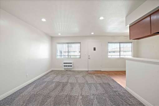 A spacious room with a grey carpet and white walls.