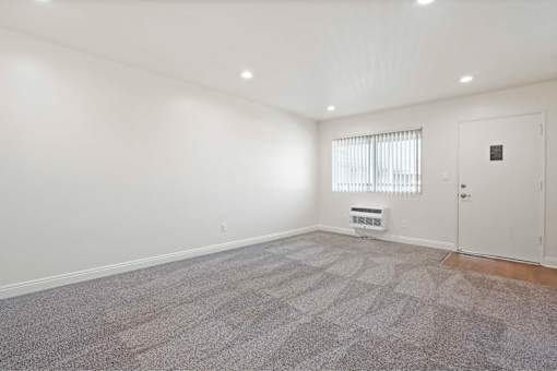 A room with a carpeted floor and a window with blinds.