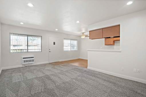 A room with a carpeted floor and a window with blinds.