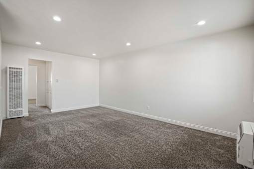 A room with a grey carpet and a white wall.