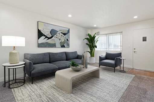 A grey sofa with a grey cushion and a grey chair with a black base.