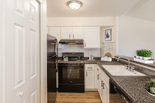 A kitchen with a black refrigerator and white cabinets.