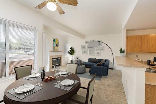 A dining room with a table set for two and a kitchen area in the background.