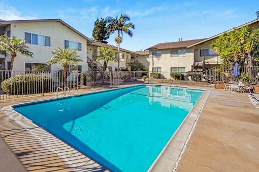 A swimming pool in a residential area with houses and palm trees.