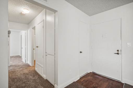 A long hallway with white doors and carpeted floors.