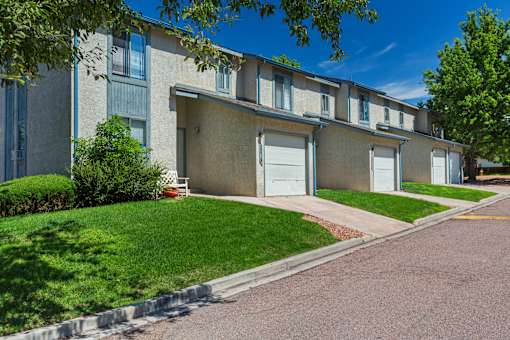 A row of apartment buildings with green lawns in front.
