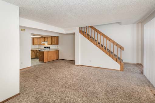 A spacious living room with a staircase leading to the upper floor.