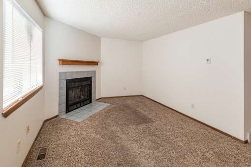 A living room with a fireplace and carpeted floor.