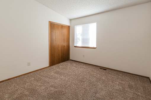 A room with a brown door and carpeted floor.