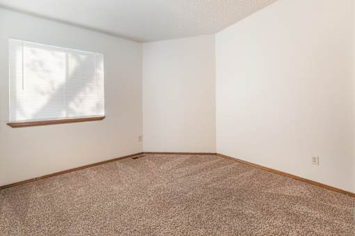 A room with a window and carpeted floor.