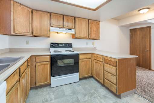 A kitchen with wooden cabinets and a white stove top oven.