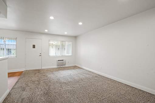 A room with a carpeted floor and a window with blinds.