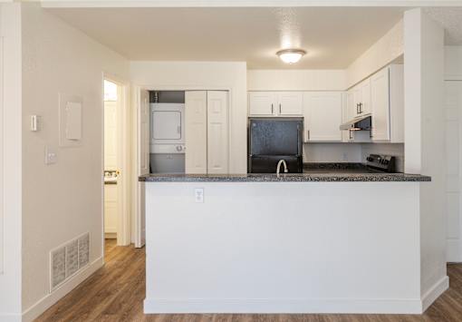 A kitchen with white cabinets and a black countertop.