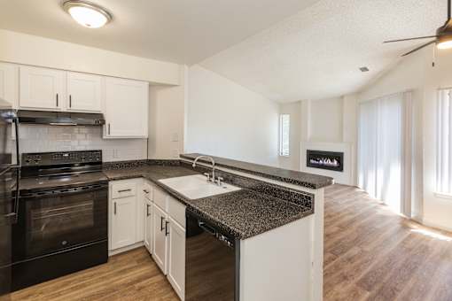 A kitchen with black appliances and white cabinets.