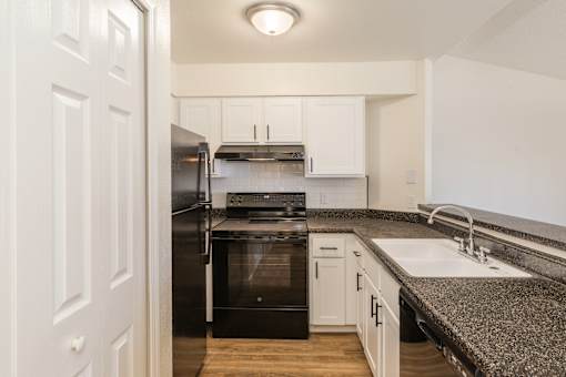A kitchen with white cabinets and a black stove top oven.