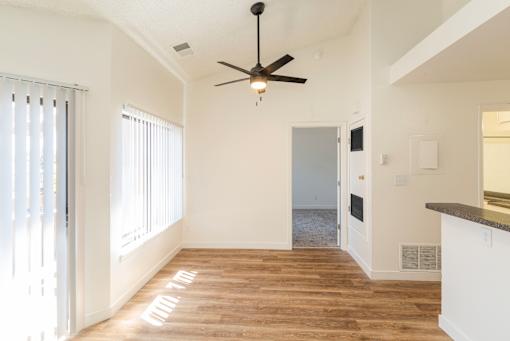 A room with a ceiling fan and a door leading to another room.