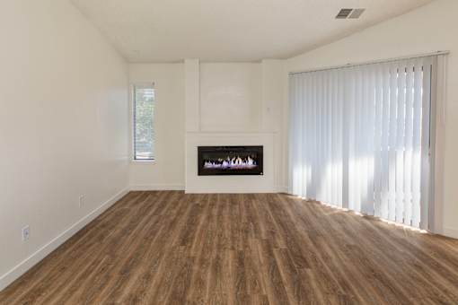 A living room with a fireplace and wooden floors.
