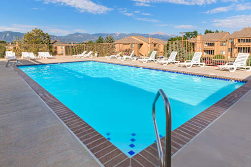 A swimming pool with a ladder and sun loungers.