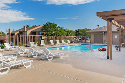 A pool area with sun loungers and a building in the background.