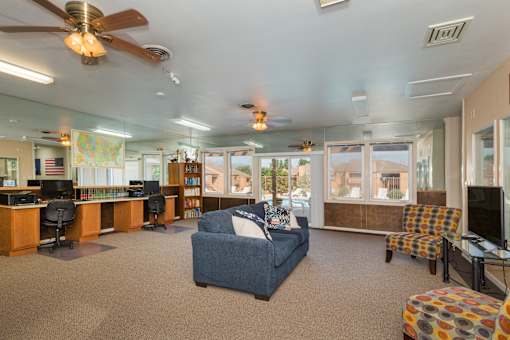 A spacious living room with a blue couch and a ceiling fan.