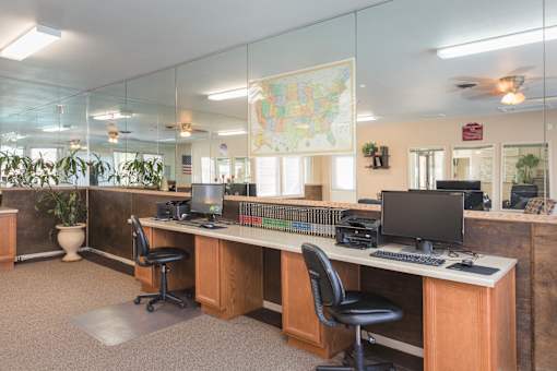 A room with a map of the United States on the wall and two desks with computers and monitors.