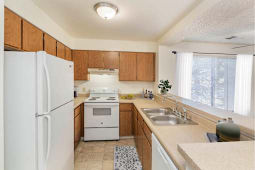 A kitchen with a white refrigerator, stove, and sink.