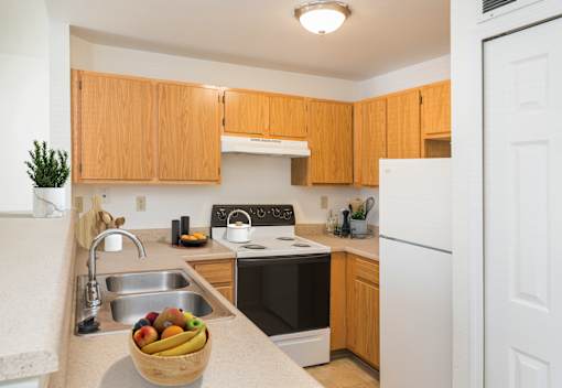 A kitchen with wooden cabinets and a bowl of fruit on the counter.